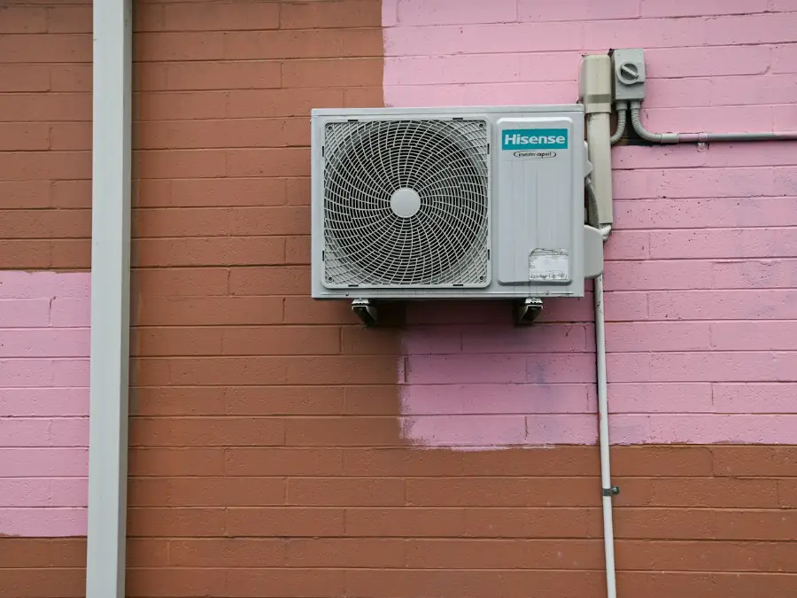 Outdoor air conditioning unit fitted on a wall bracket outside a house