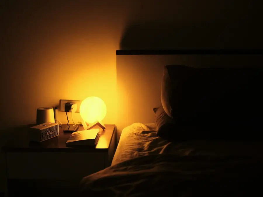 Bedside lamp glowing on a side table next to a bed