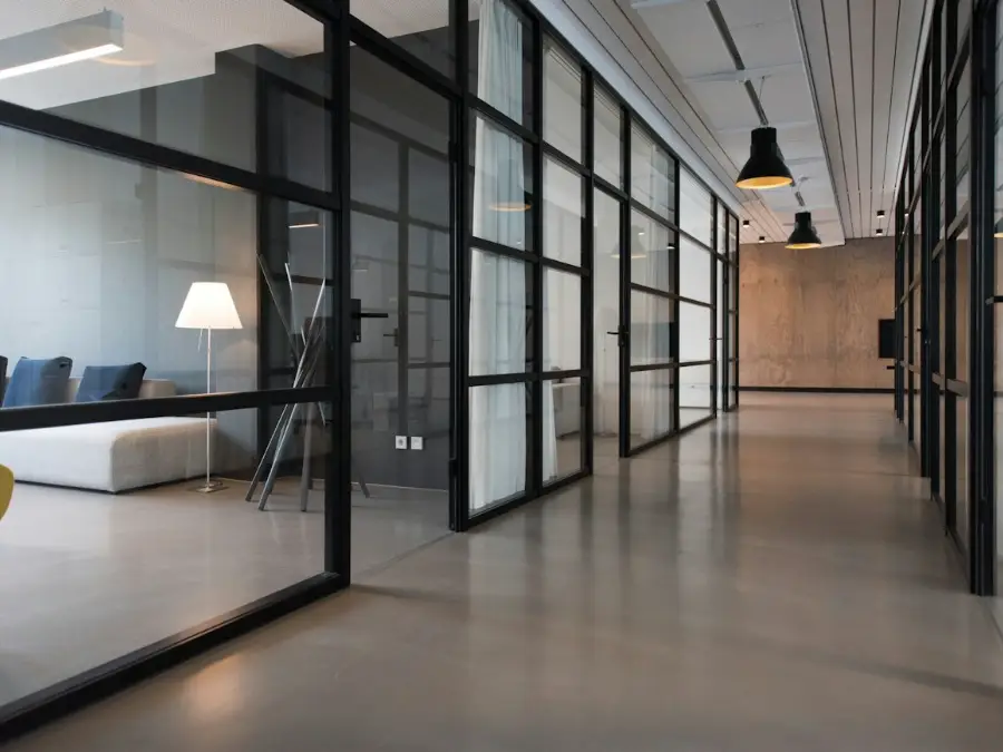 Office with glass partition walls separating meeting rooms from open plan desks