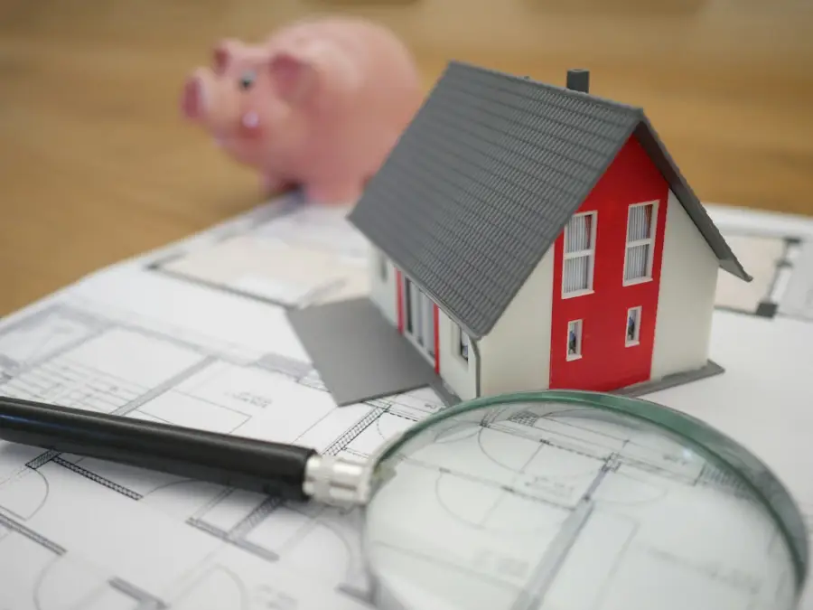 Small model house on a table next to planning papers