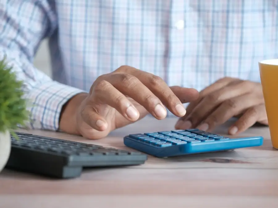 Hands typing air conditioning prices into a calculator